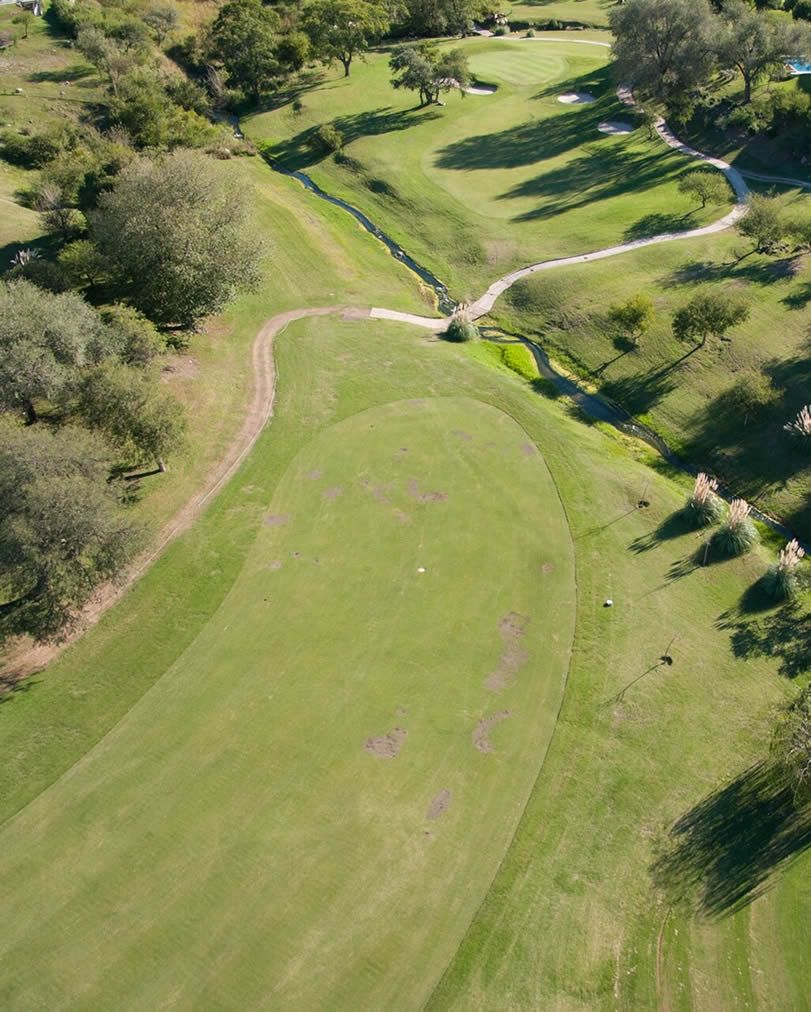 Una vista aérea de un campo de golf rodeado de árboles y césped.