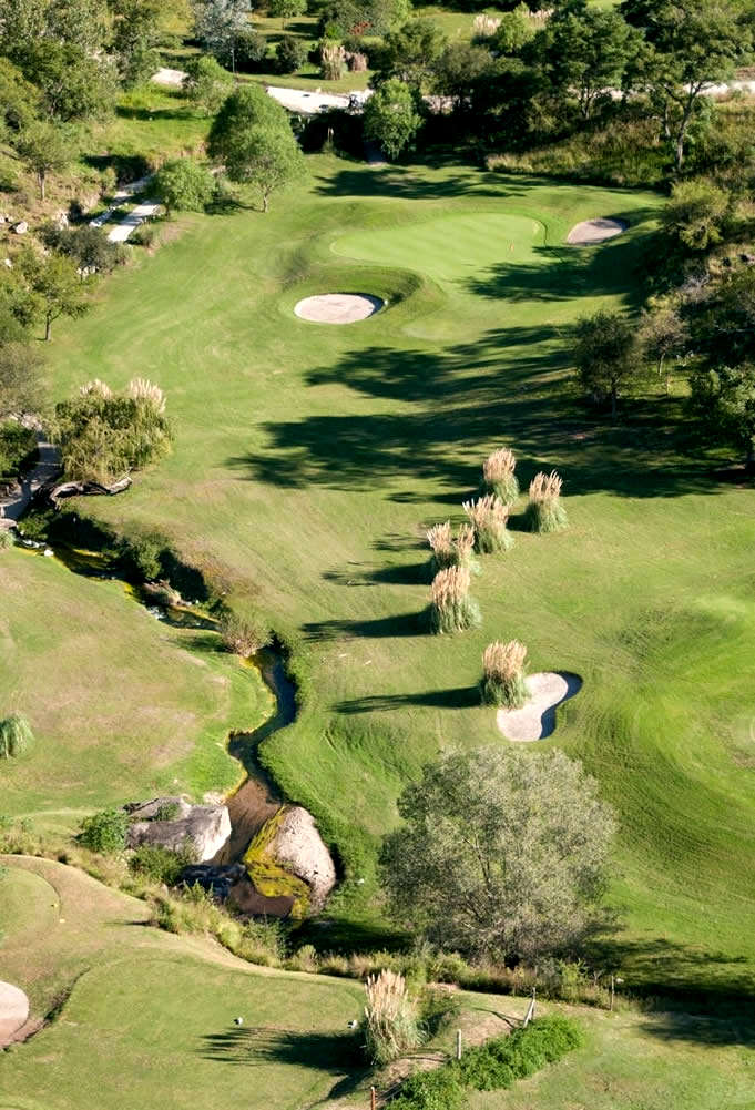 Una vista aérea de un campo de golf con un río que lo atraviesa.