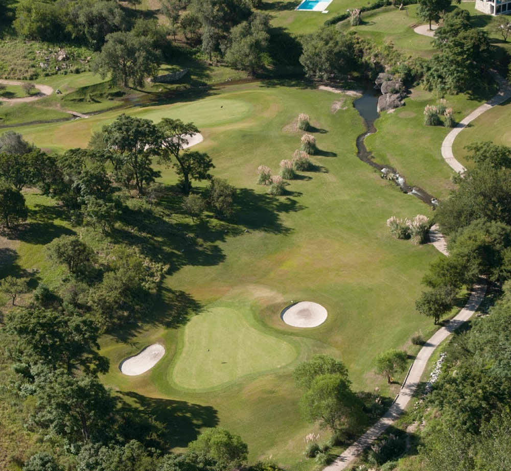 Una vista aérea de un campo de golf rodeado de árboles.