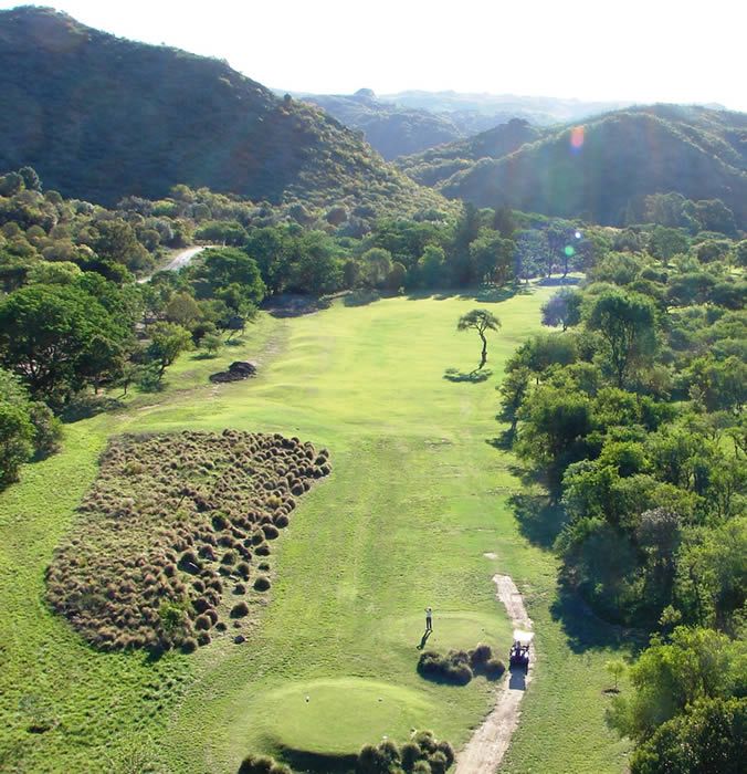 Una vista aérea de un campo de golf con montañas al fondo.
