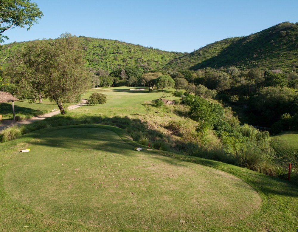 Una vista de un campo de golf con montañas al fondo.