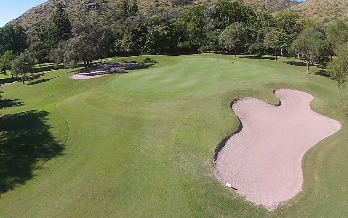 Vista aérea de un campo de golf con un bunker en medio.