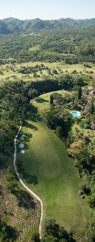Una vista aérea de un campo de golf rodeado de árboles y montañas.