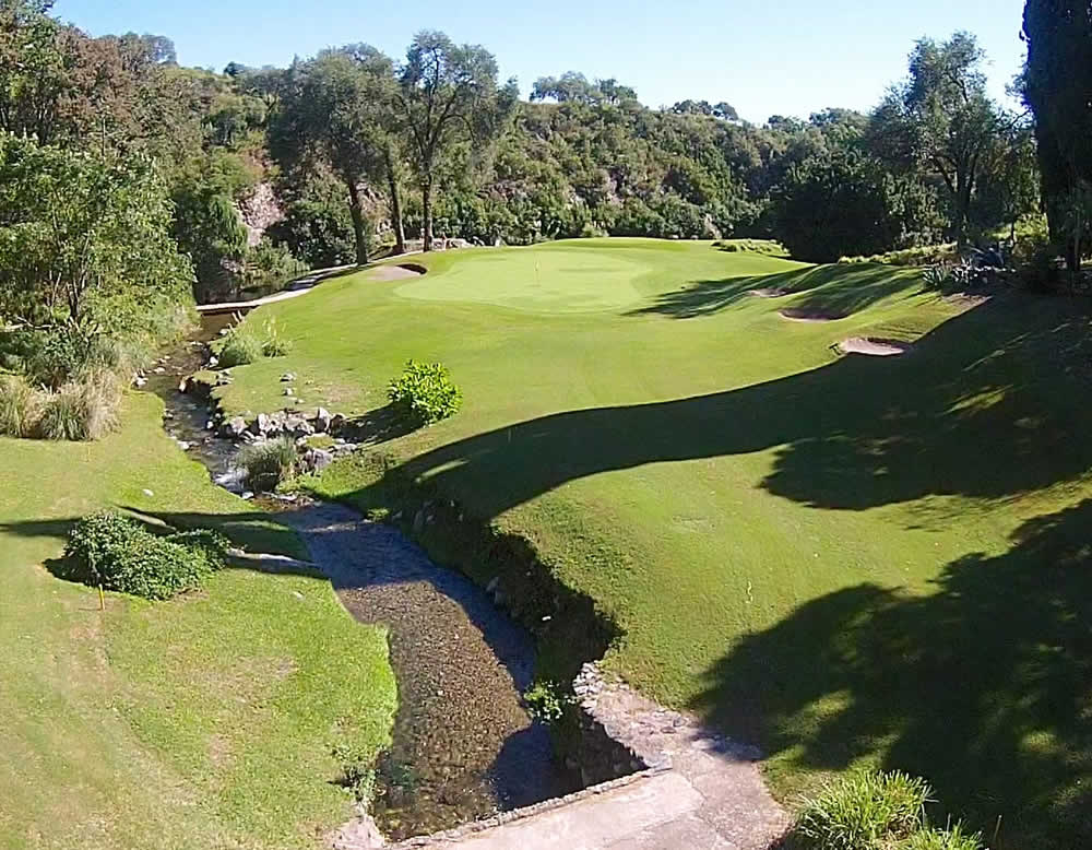 Una vista aérea de un campo de golf con un arroyo que lo atraviesa.