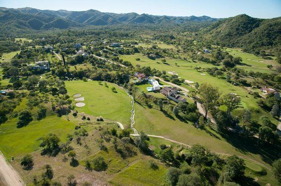 Una vista aérea de un campo de golf con montañas al fondo.
