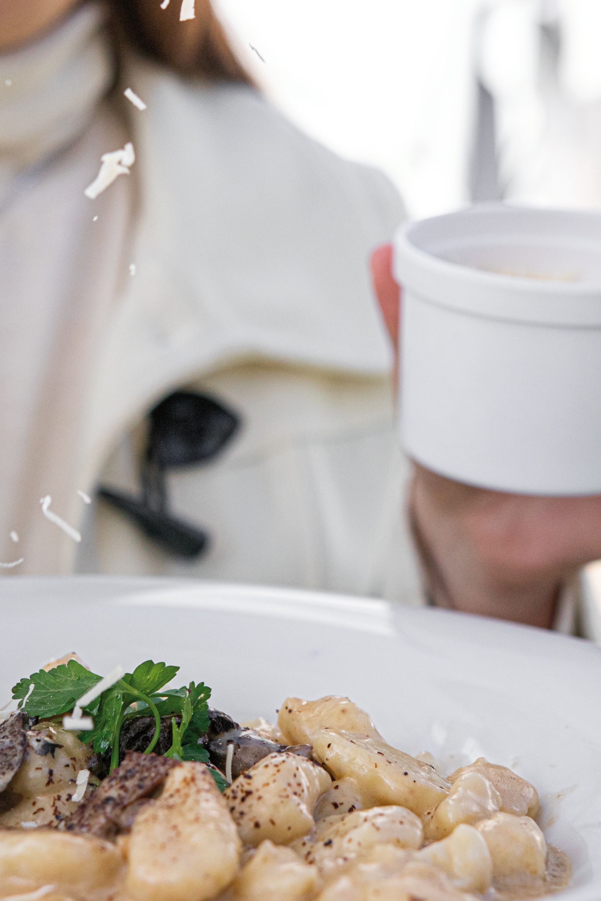 Una mujer sostiene una taza de café y un plato de comida.