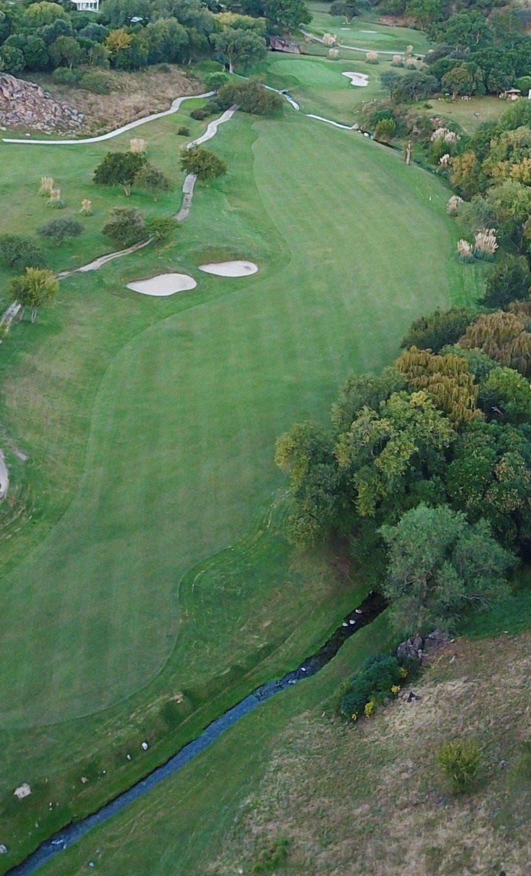 Una vista aérea de un campo de golf con un río que lo atraviesa.