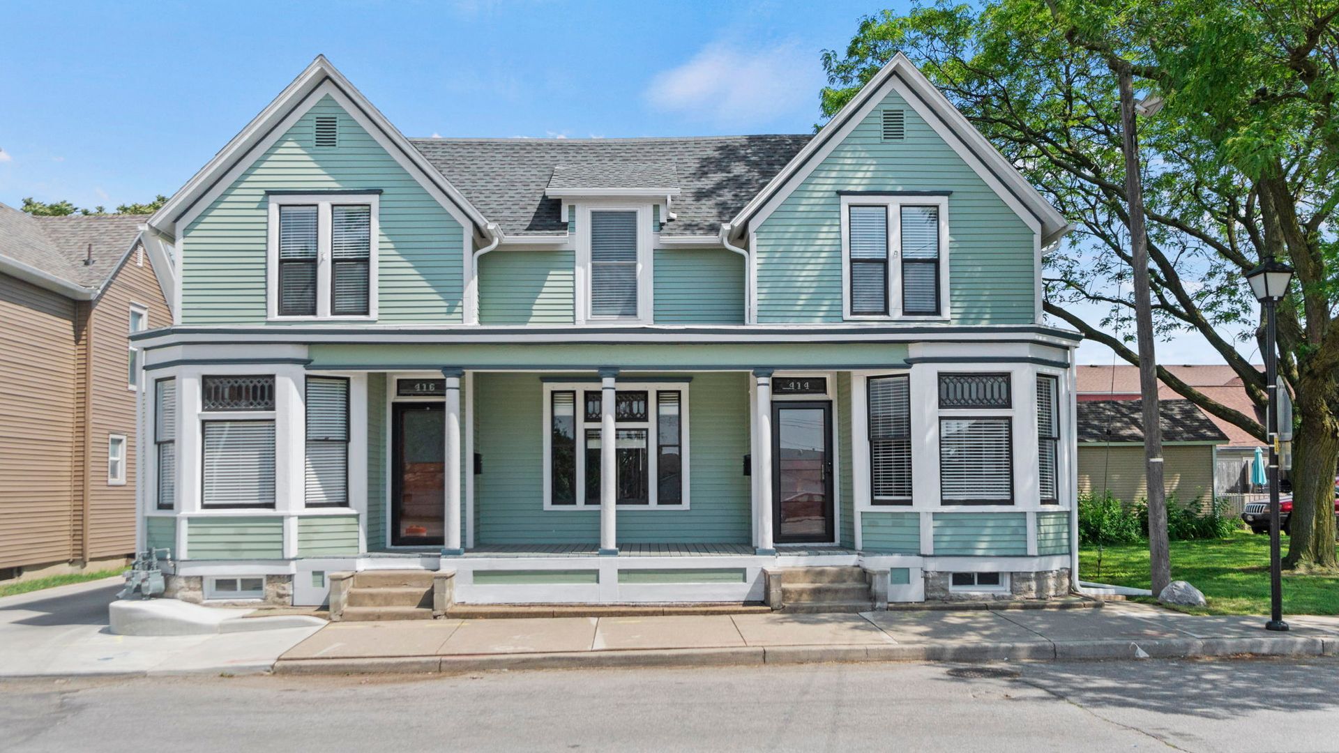 A large green house with a porch and a lot of windows