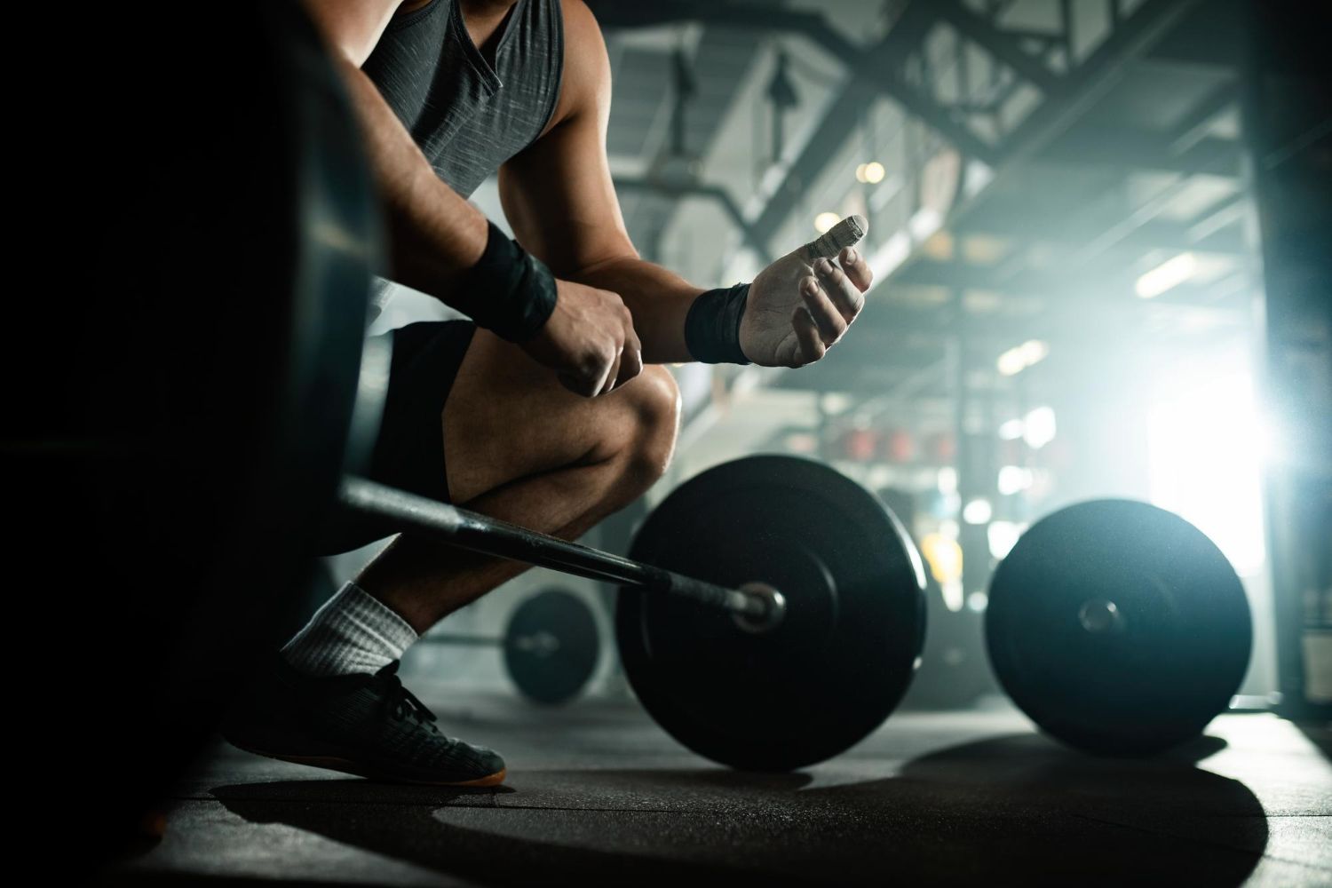 A man is squatting down with a barbell in a gym.