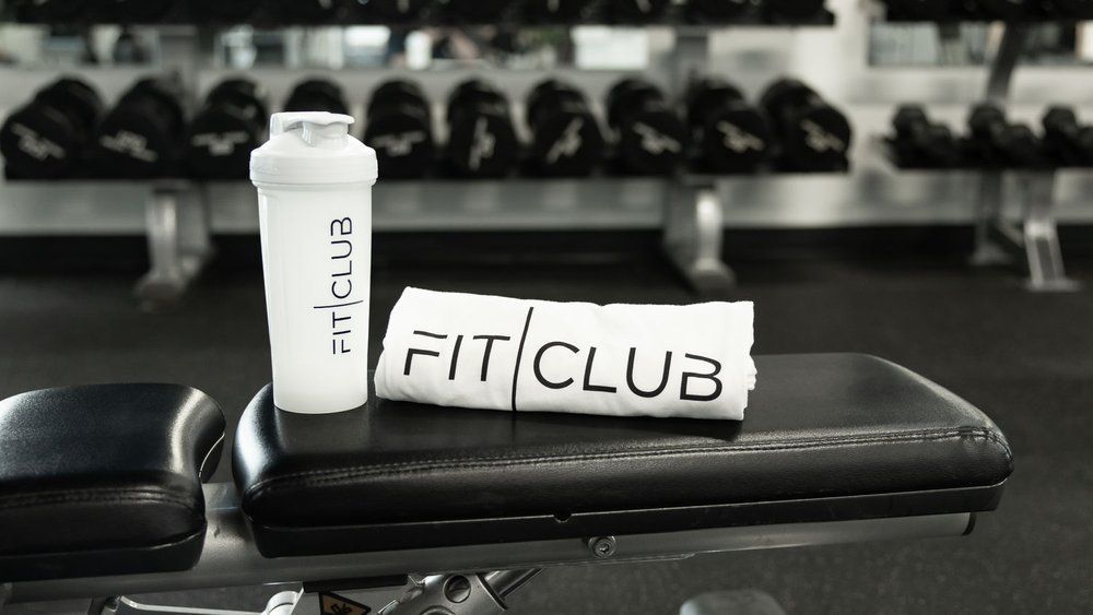 FitClub-branded shaker bottle and towel on a gym bench for post-workout recovery in Salem, Utah.