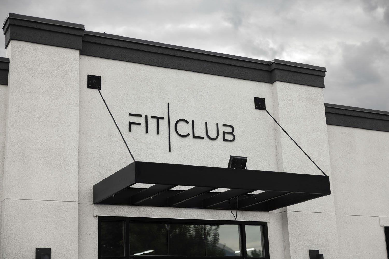 A white building with a black awning that says fit club