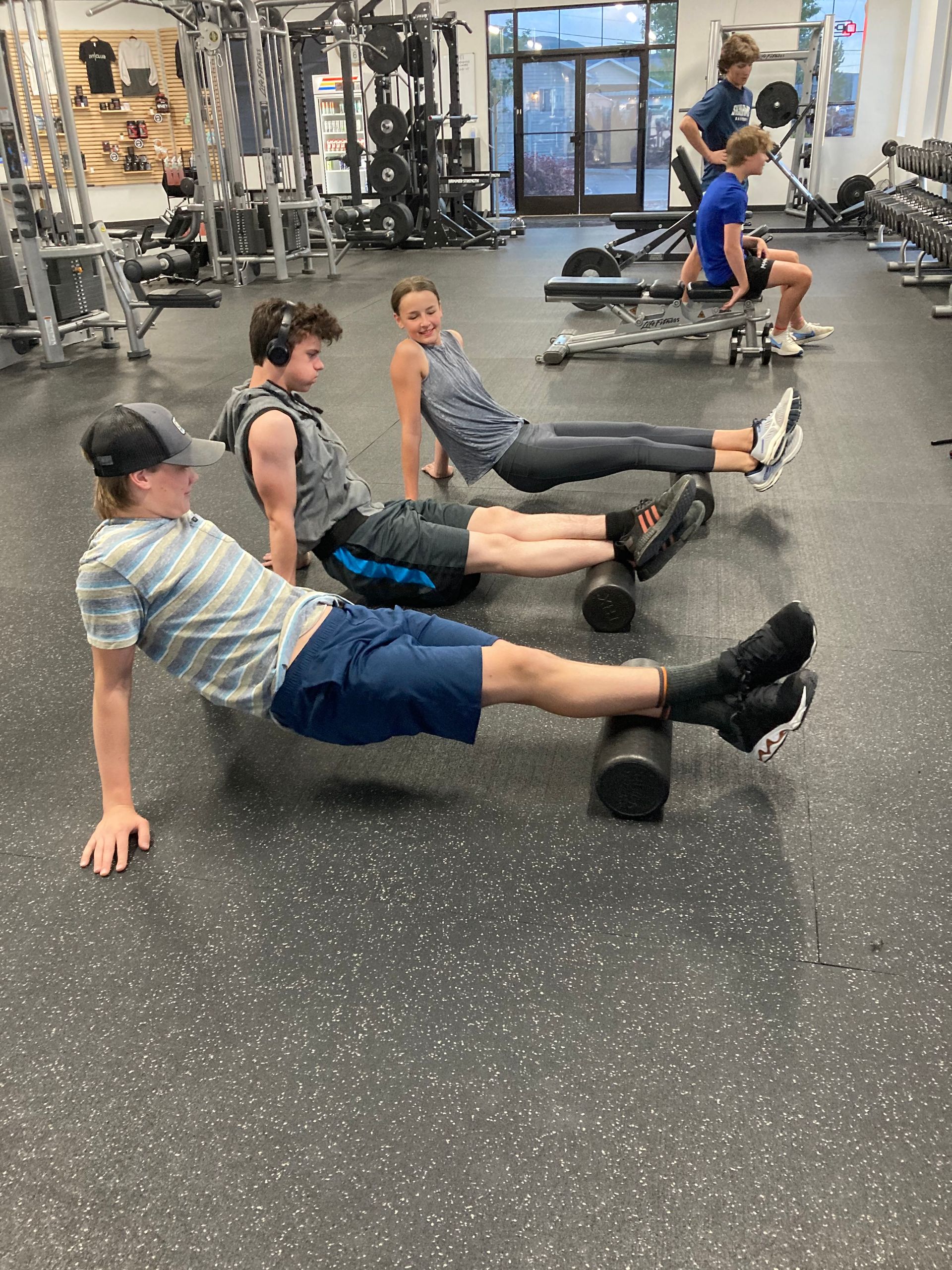 Teen fitness class at FitClub in Salem, Utah, using foam rollers for recovery.
