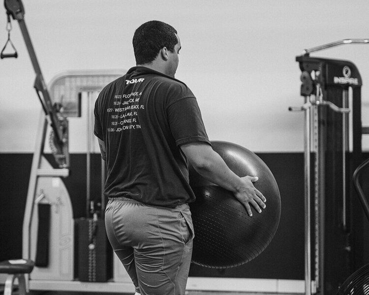 FitClub member holding exercise ball for core and stability workout.