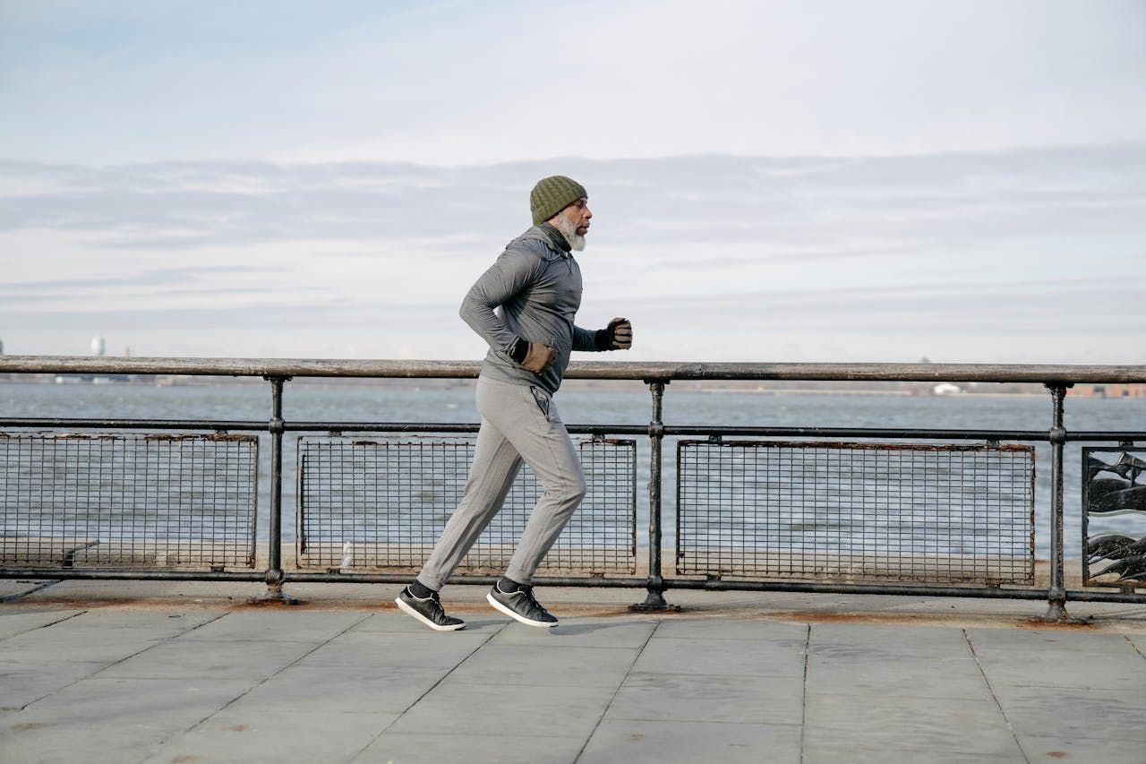 A man is running on a pier next to a body of water.