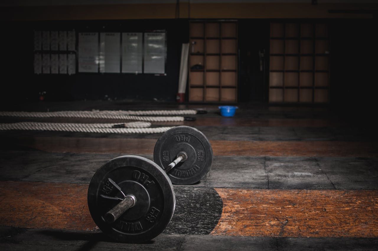 A barbell is laying on the floor in an empty gym.