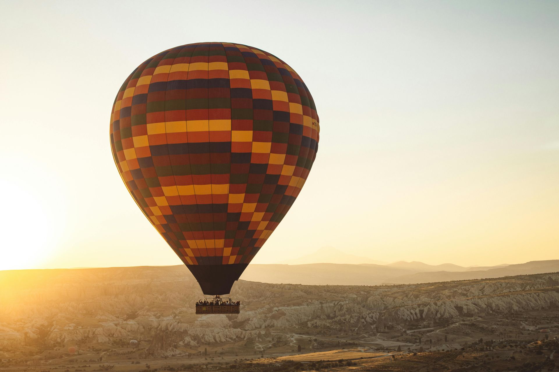 A hot air balloon is flying over a valley at sunset.