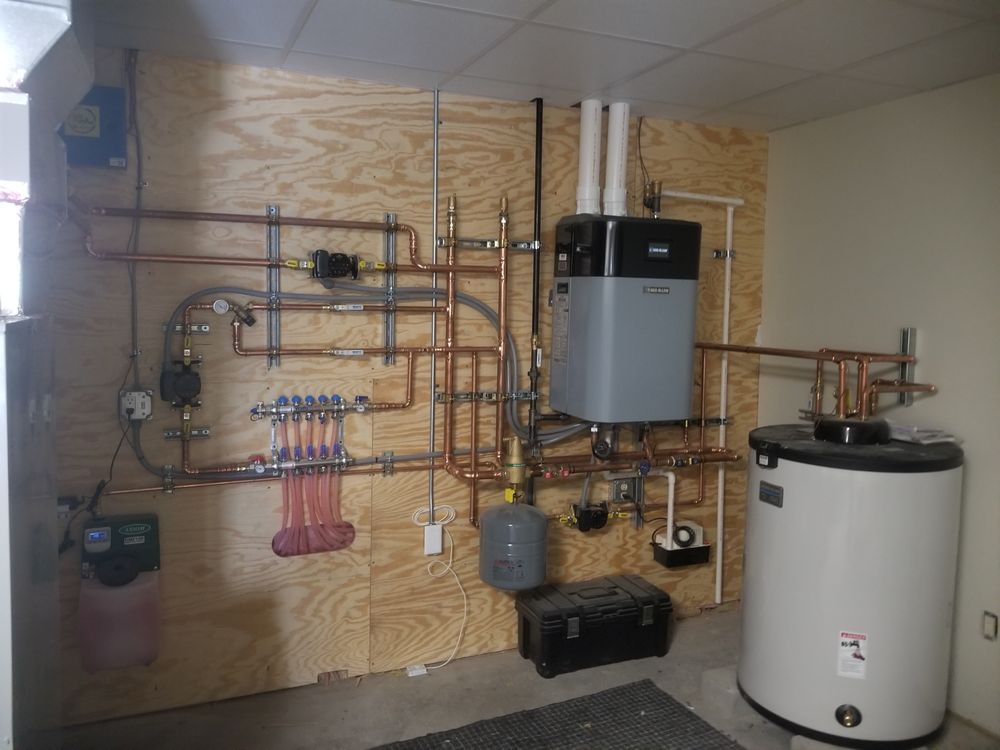 A room with a water heater and a boiler on the wall.