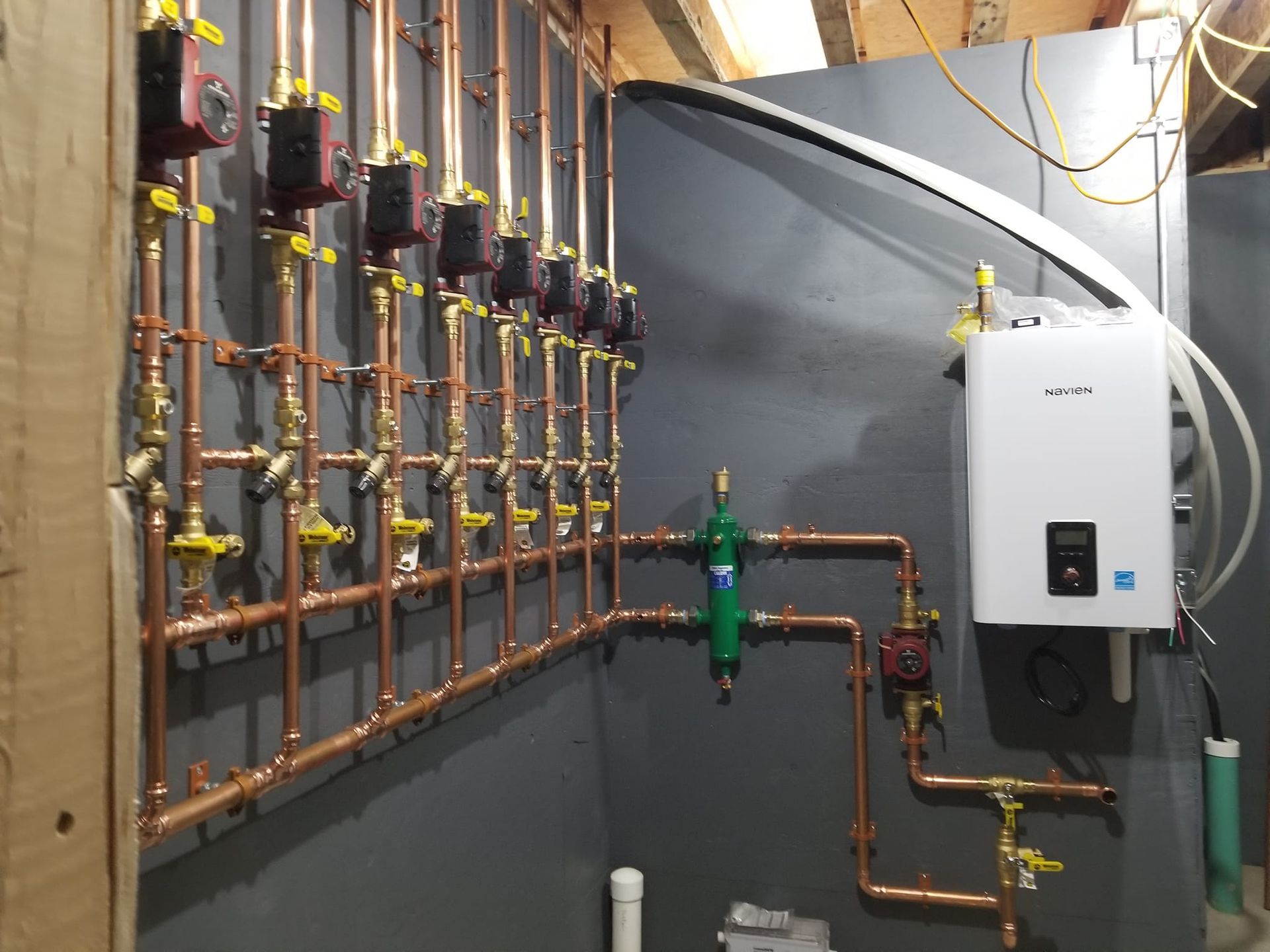 A room with copper pipes and a boiler on the wall