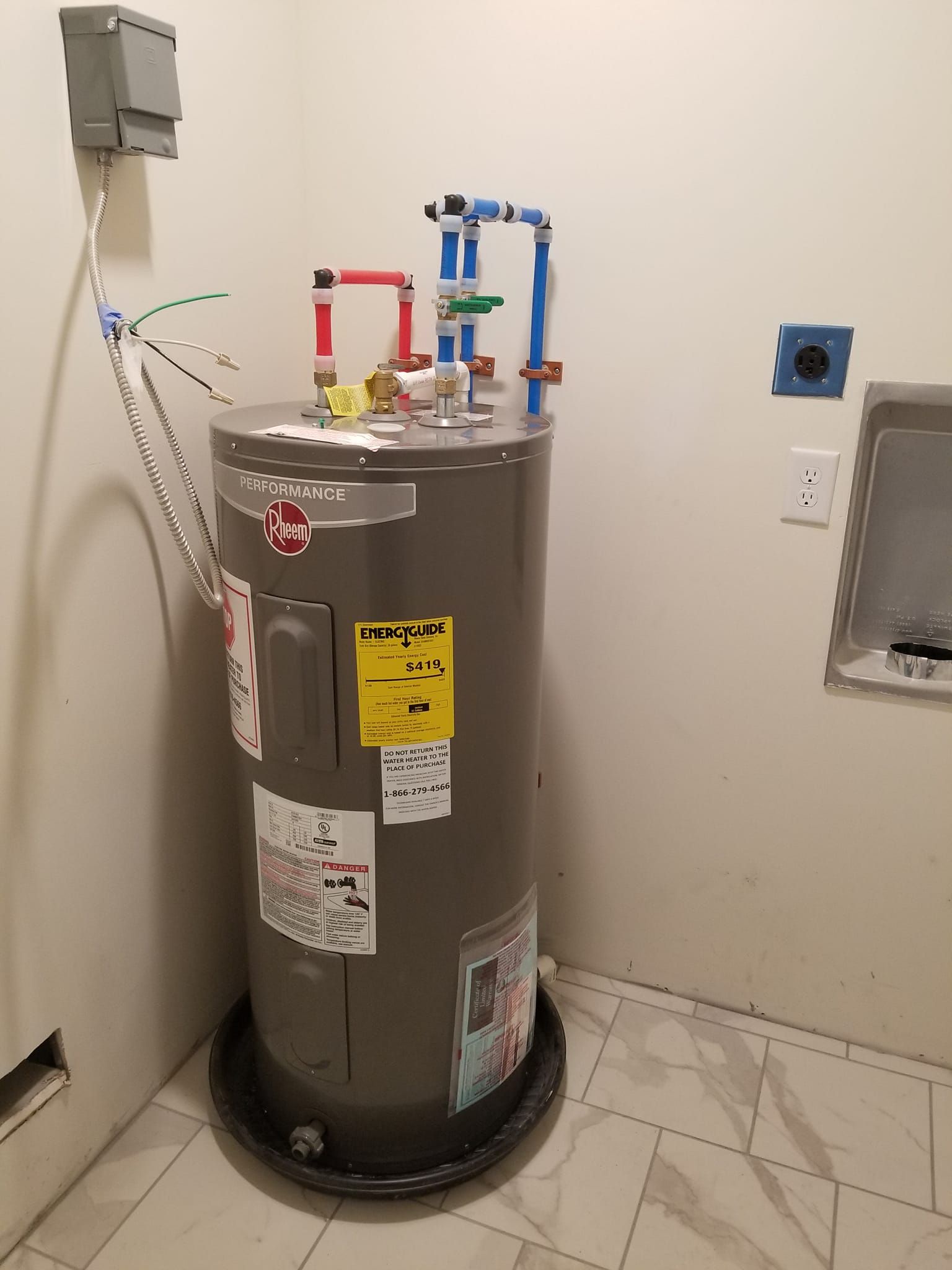 A water heater is sitting in a corner of a room.