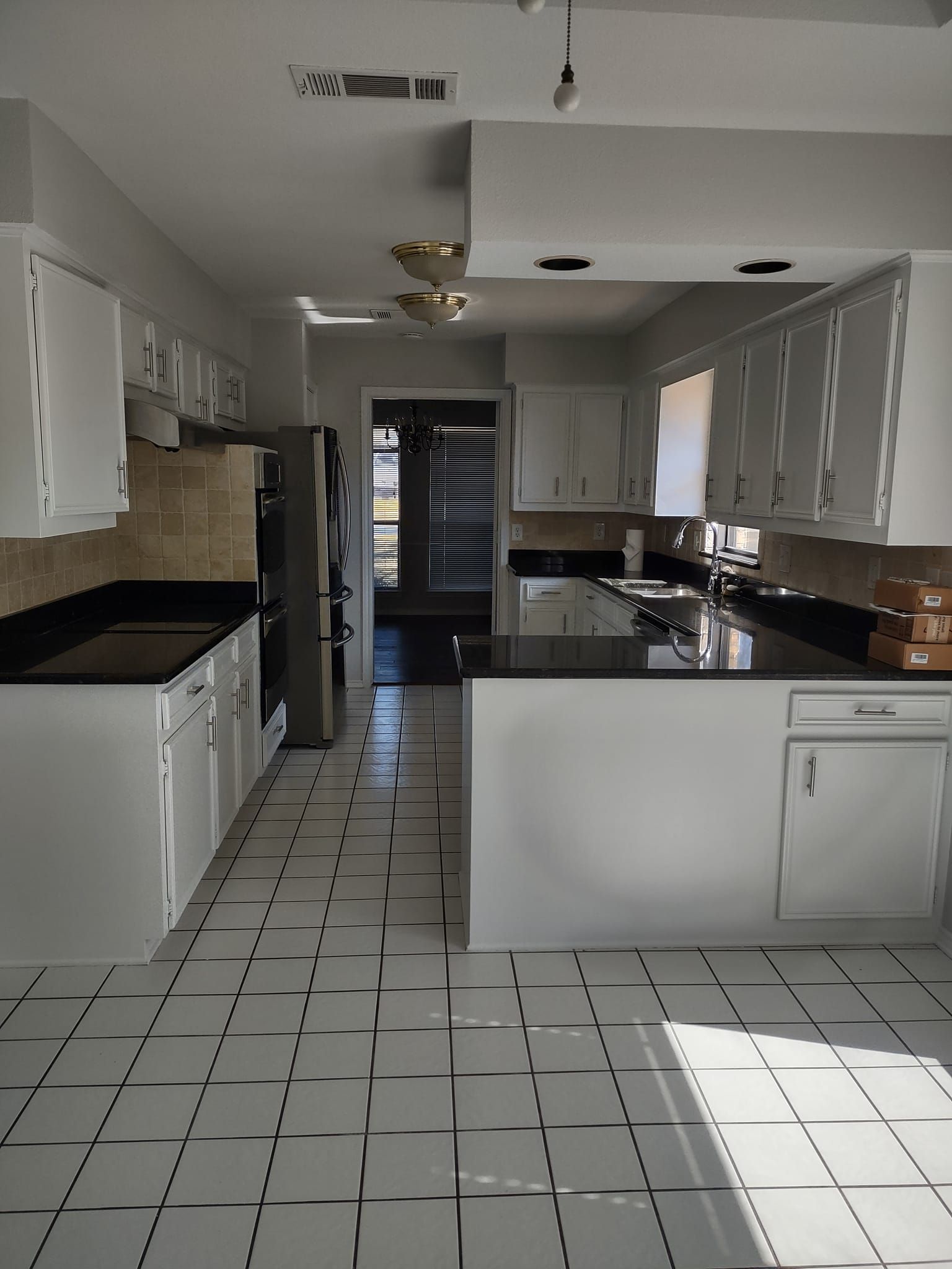 A kitchen with white cabinets and black counter tops