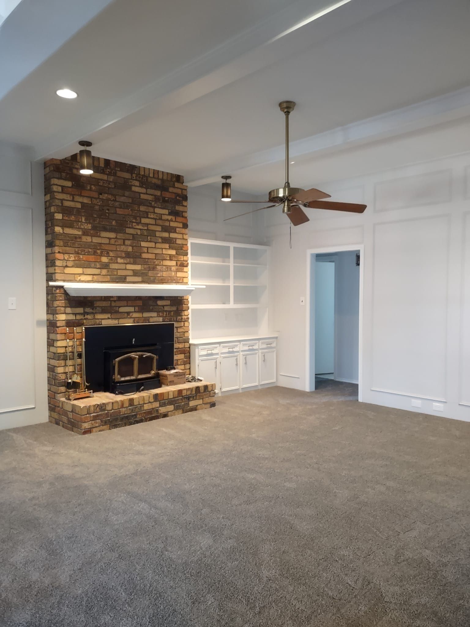 A living room with a fireplace and a ceiling fan