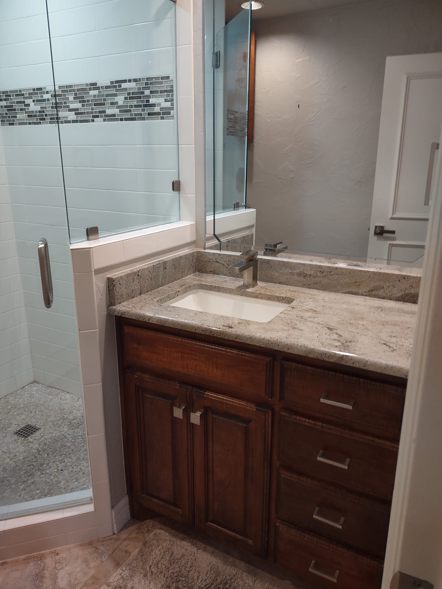 A bathroom with a sink , mirror and shower.