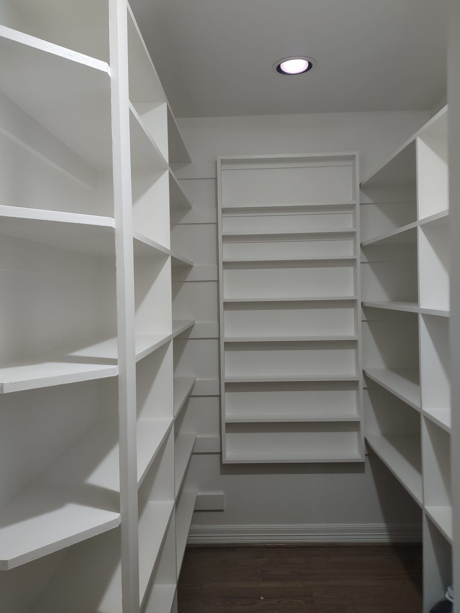 A walk in closet with lots of shelves and a light on the ceiling.