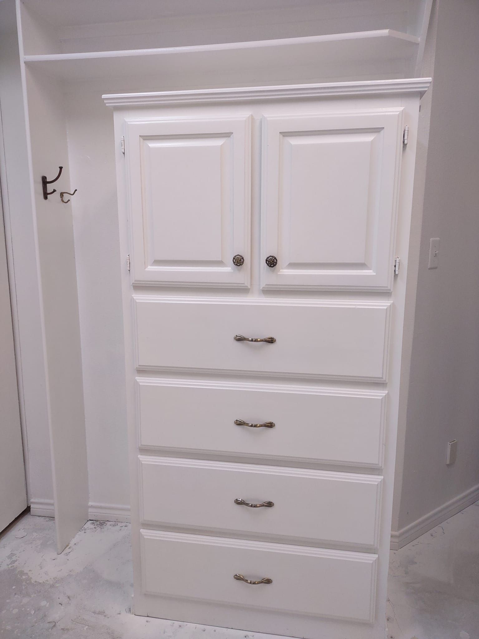 A white dresser with drawers and cabinets in a room.