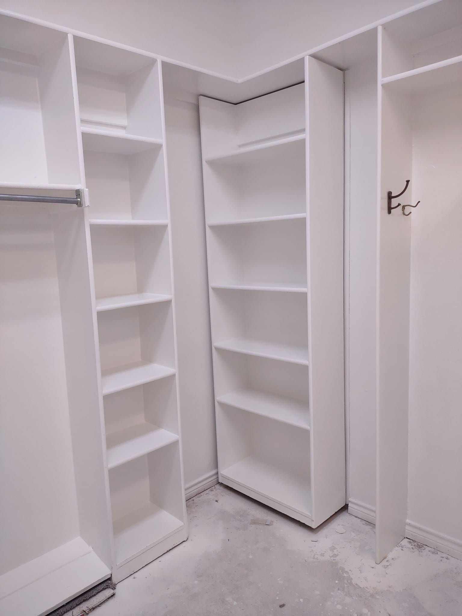 A walk in closet with lots of shelves and hooks