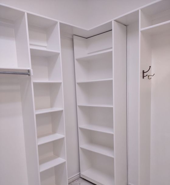 A walk in closet with lots of shelves and hooks