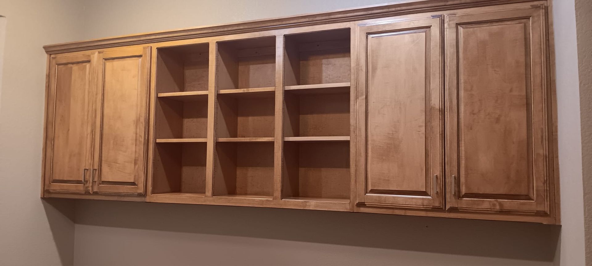 A kitchen with wooden cabinets and shelves on the wall.