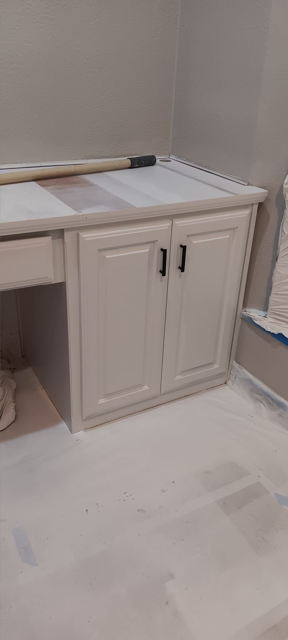 A room with a desk , cabinets , and a bench.