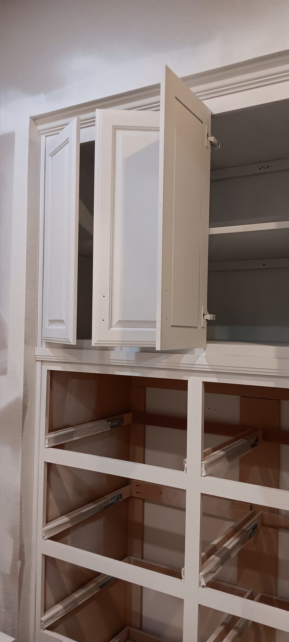 A closet with a lot of shelves and a door open.