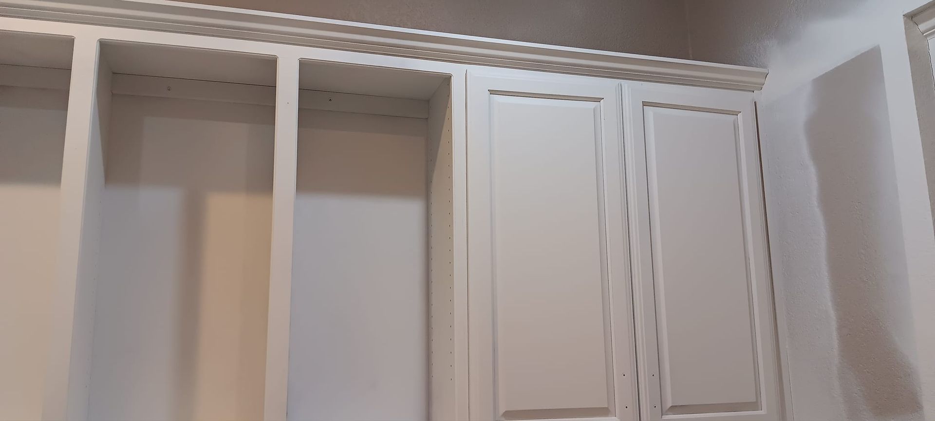 A close up of a closet with white cabinets and shelves.