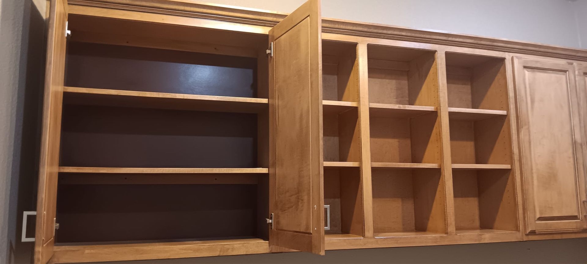 A kitchen cabinet with the doors open and empty shelves.