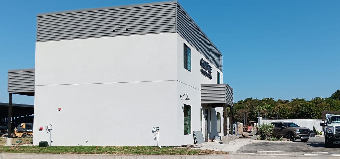 A white building with cars parked in front of it on a sunny day.