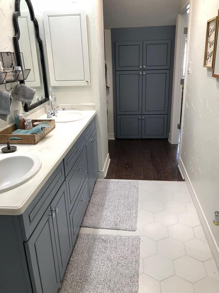 A bathroom with blue cabinets , a sink and a mirror.
