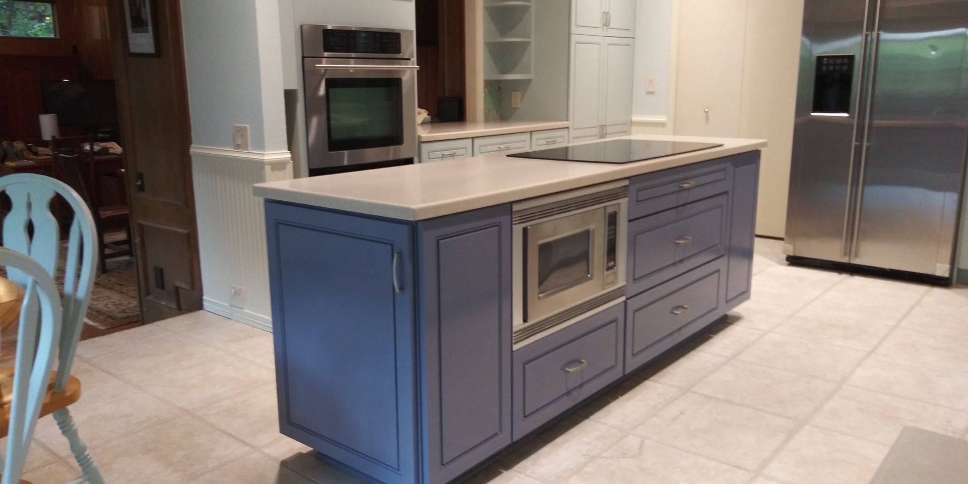 A kitchen with blue cabinets , stainless steel appliances and a large island.