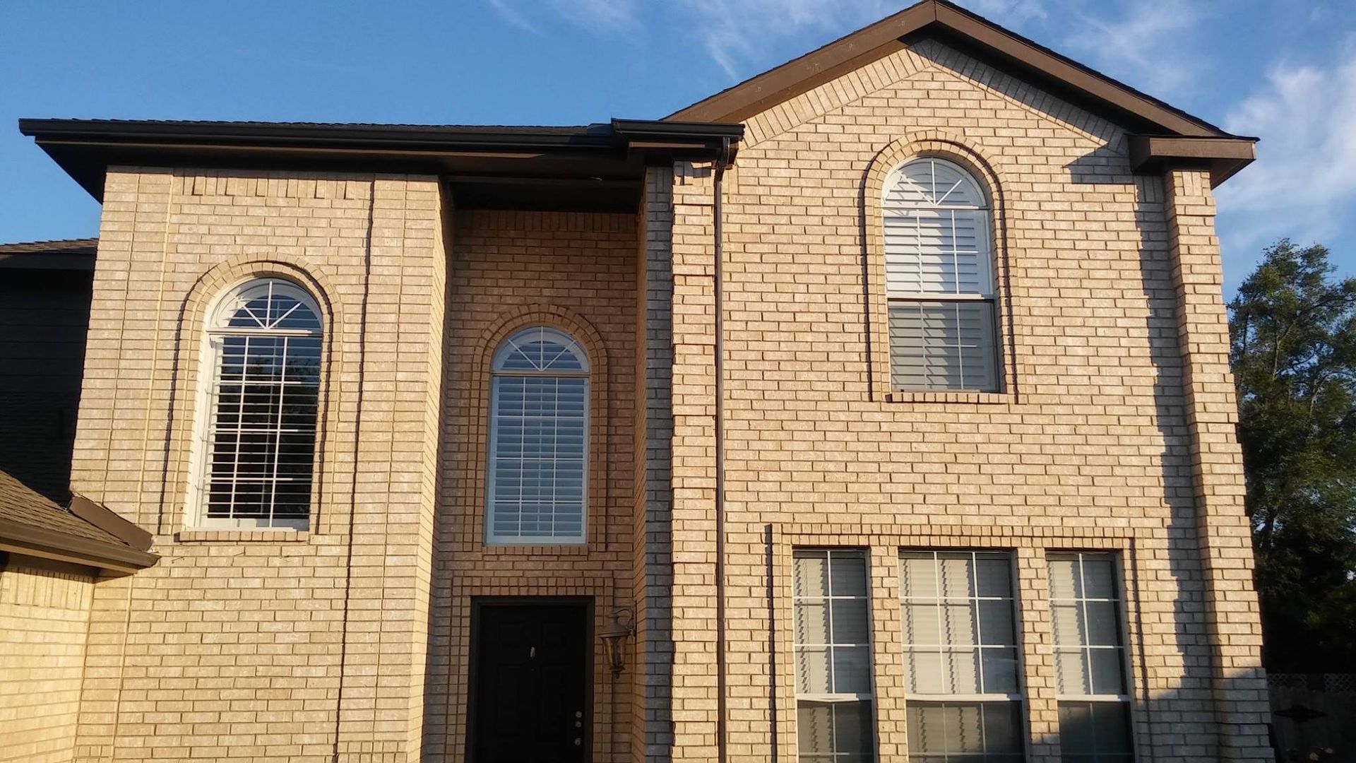 A large brick house with arched windows on a sunny day