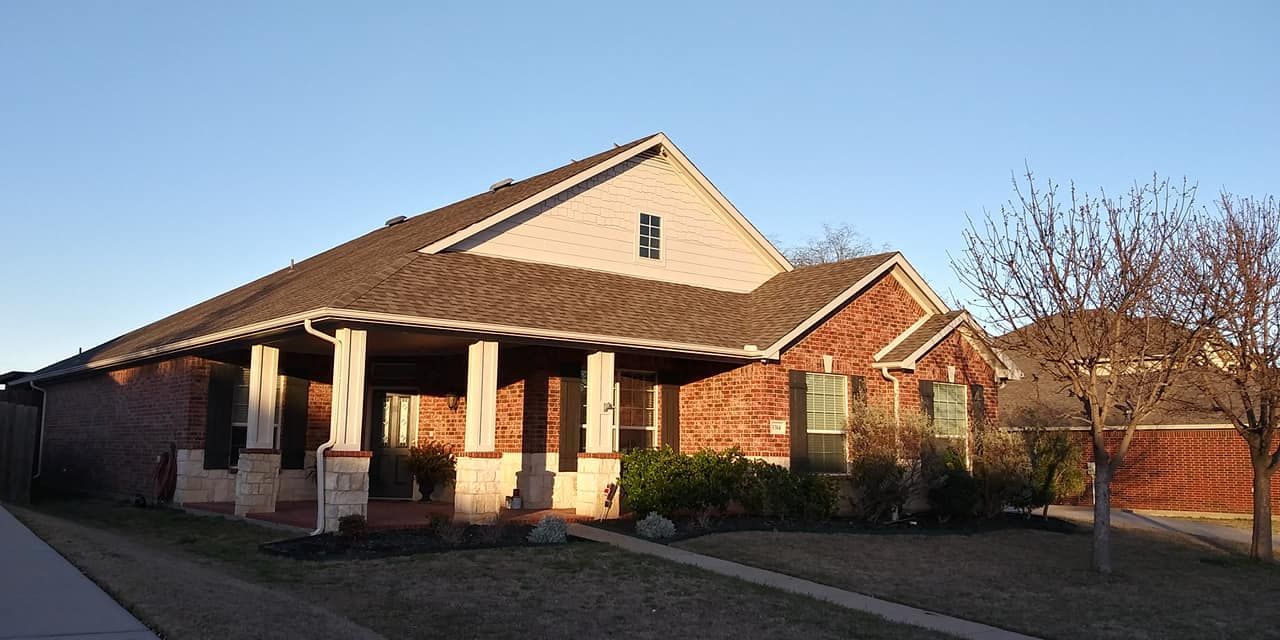 A brick house with a brown roof and a porch