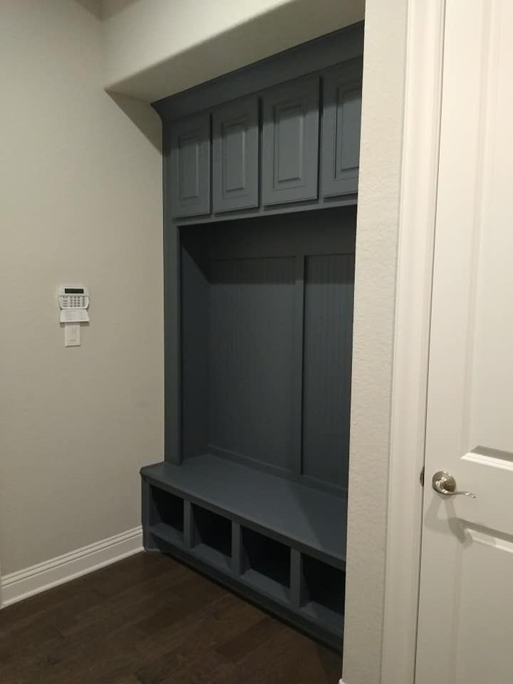 A mud room with a bench and cabinets in a house.