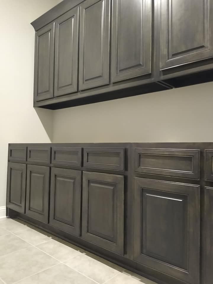A laundry room with a lot of gray cabinets and drawers.