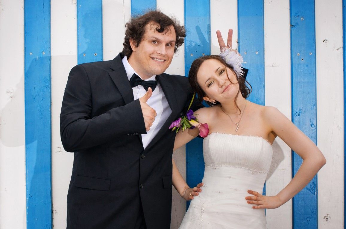 A bride and groom are posing for a picture in front of a blue and white striped wall.