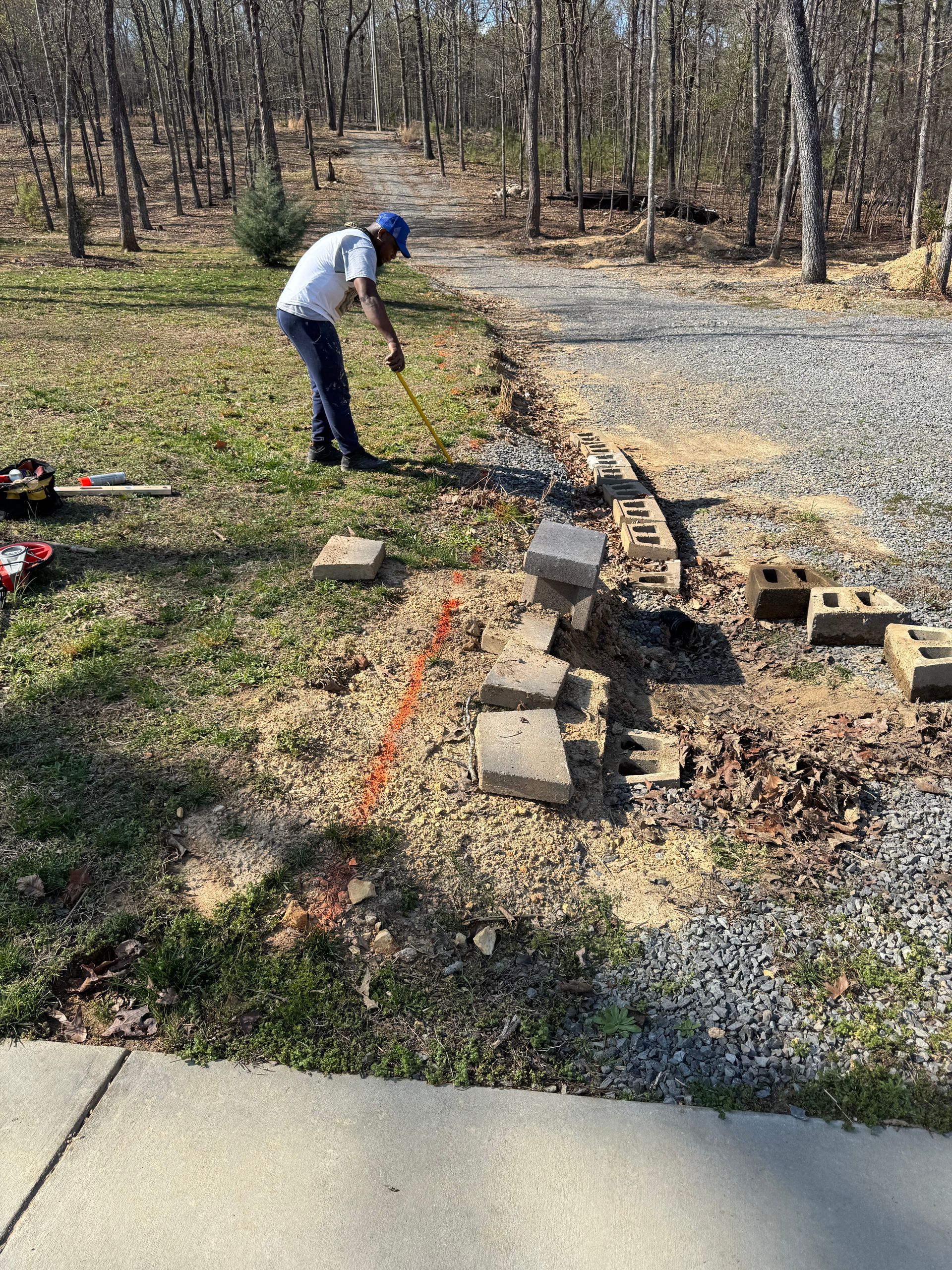 A man is standing in the grass next to a sidewalk.