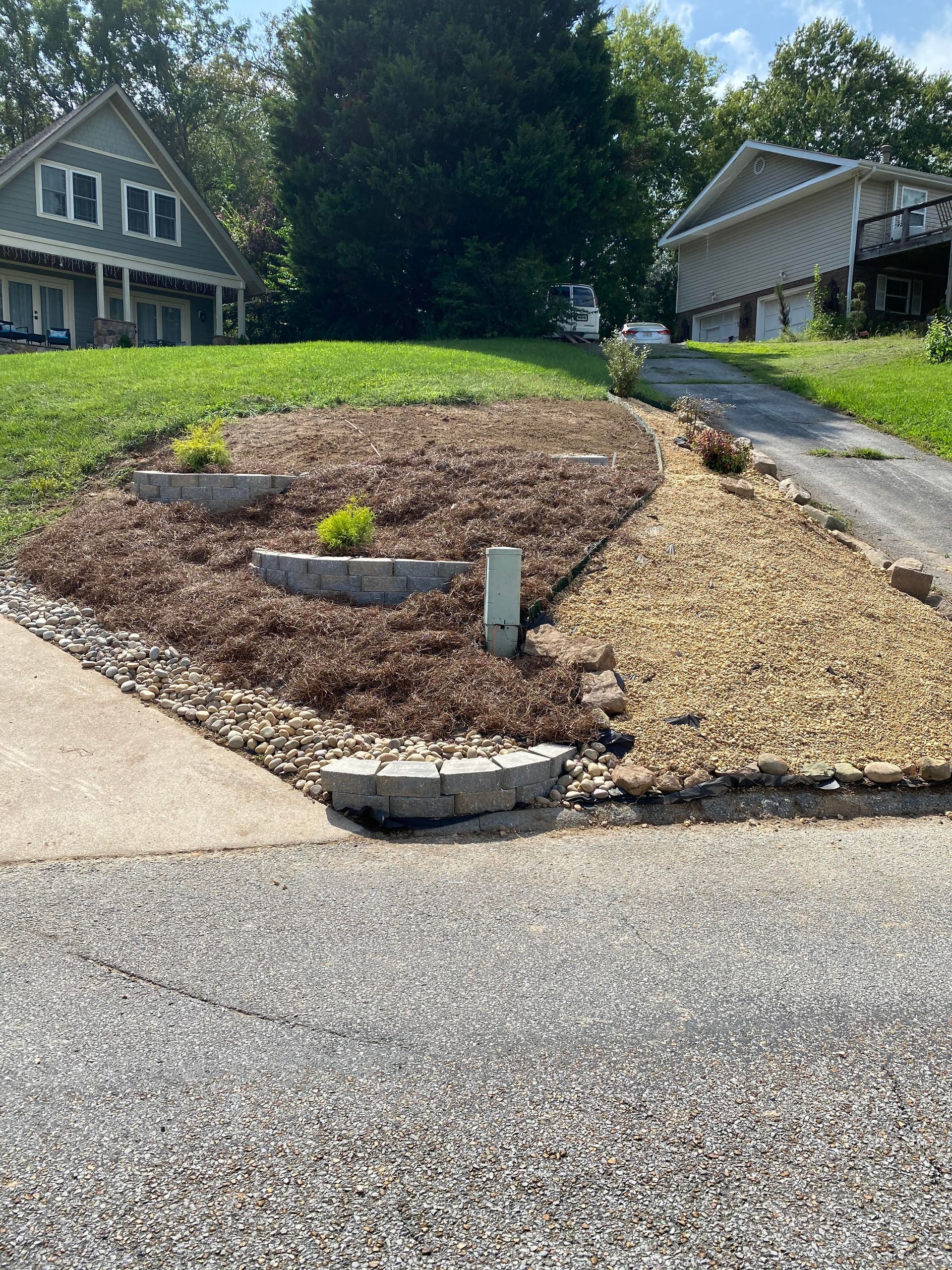 A house is sitting on top of a hill next to a driveway.