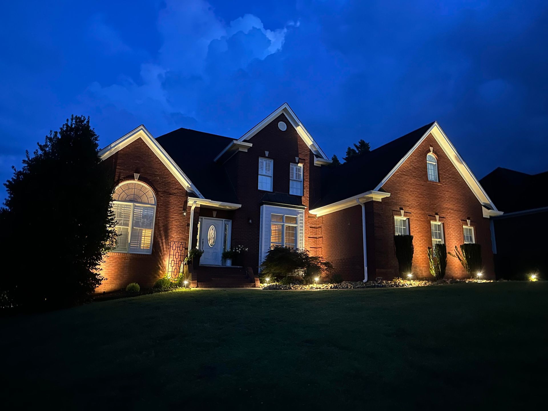 A large brick house is lit up at night.