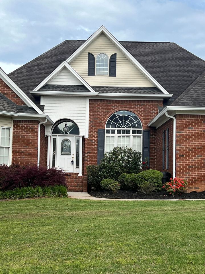 A large brick house with a large lawn in front of it.