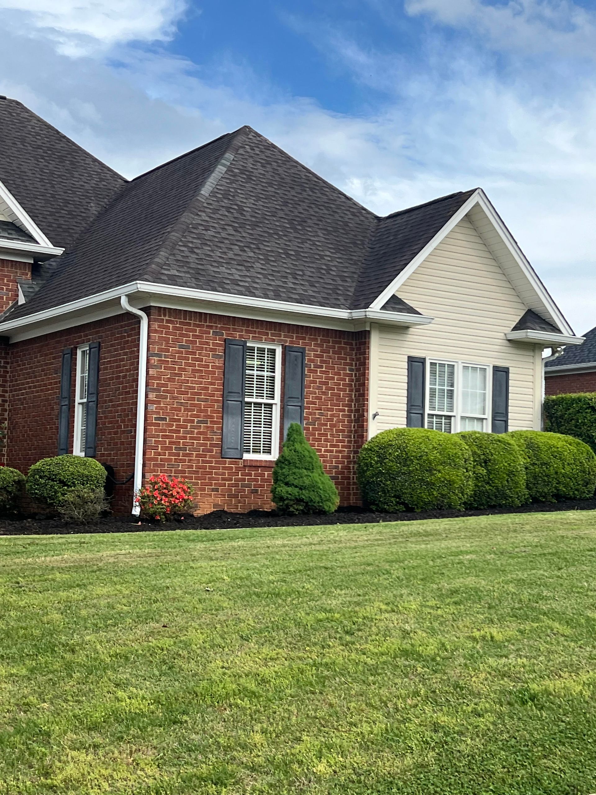 A large brick house with a lush green lawn in front of it.