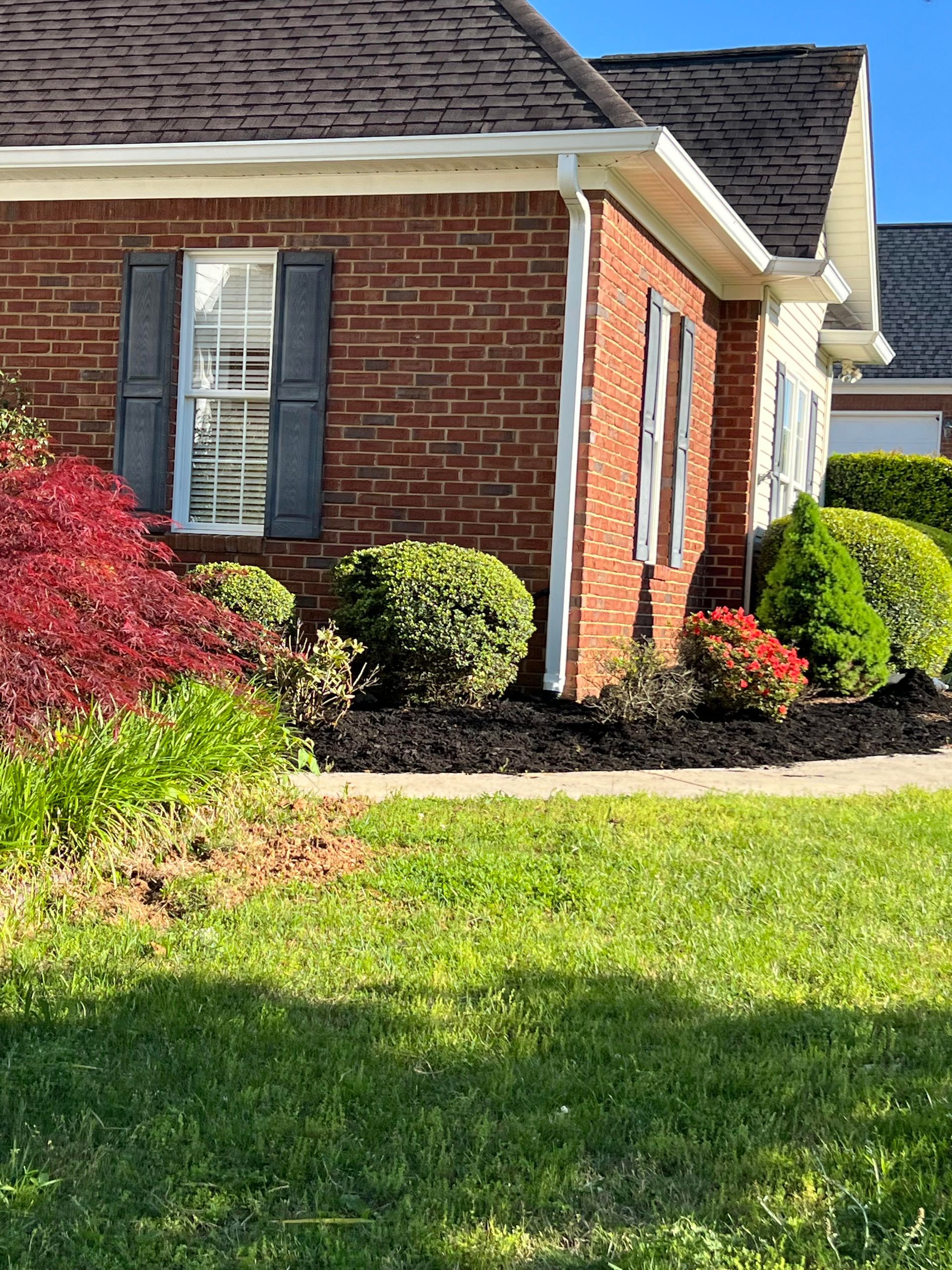 A brick house with a lush green lawn in front of it.
