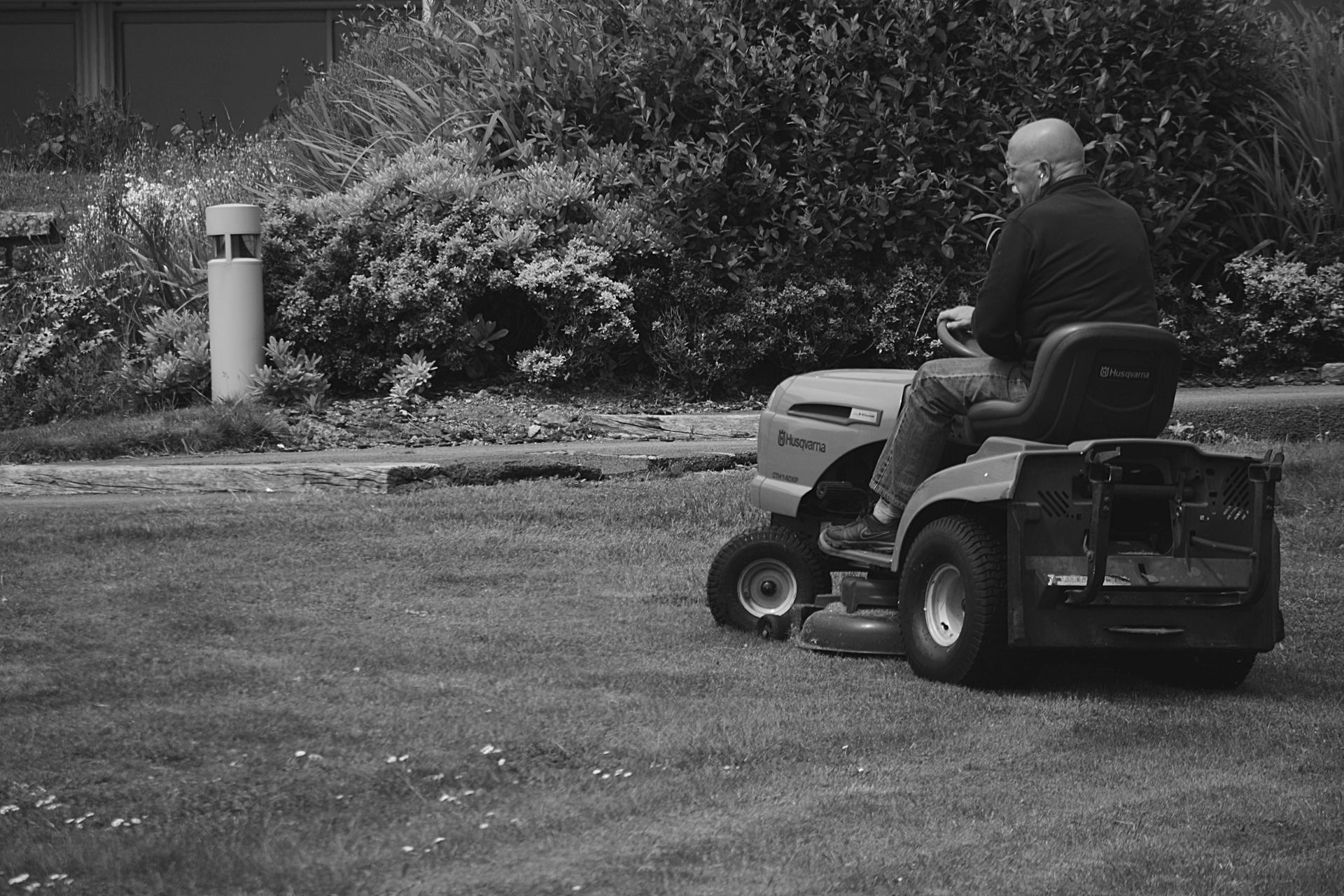 A man is riding a lawn mower on a lush green lawn.